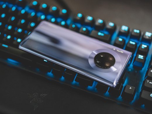 一位短发编辑坐在绿植旁的工位前写时间线，屏幕上开着多个公开信息页面，光线柔和温暖