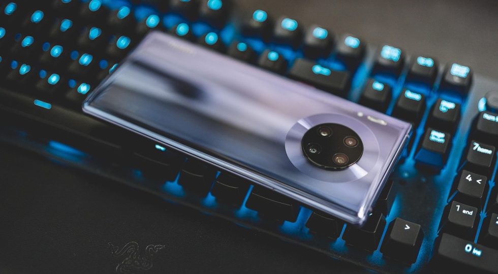 手机屏幕上一条聊天截图被红色方框圈出疑点位置，旁边放着放大镜与便签，桌面暖色调突出核查氛围